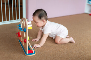 A sweet baby crawls toward a wooden toy, engaging with colors