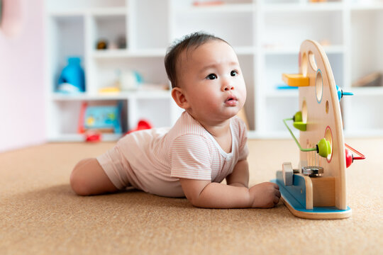 An adorable baby boy crawls on the floor, engrossed in playing