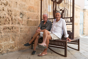 Male Gay Couple sitting on a Bench in a Historic Stone Street