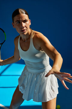 Tennis player prepares for a swift shot in bright blue court