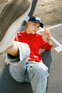 Woman in red hoodie lying on court with raised leg