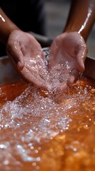 Fototapeta premium Hands cupping clear water with liquid surface below, reflecting light, creating splash