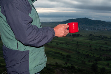Person holding red coffee mug enjoying mountain view