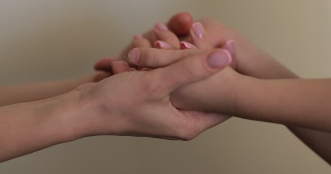 Close up of a child's hands reaching toward the mother's hands. Mother and child gently holding each other's hands and cuddling