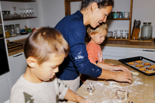 Mother and children baking christmas cookies in kitchen