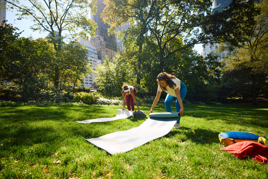Friends prepare to do yoga in the park