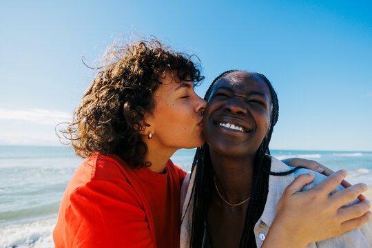 Women kissing her best friend on the cheek on beach