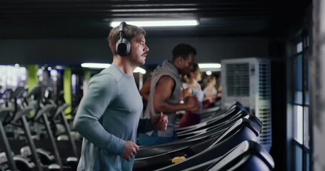 Headphones, workout and man on treadmill in gym for running, fitness or training with health. Wellness, audio tech and male person listening to music for cardio exercise on machine in sports center. - Powered by Adobe