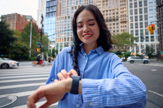 Smiling woman checks the time on her watch