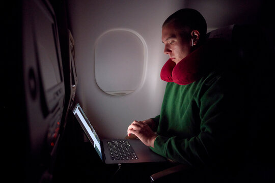 Busy man works on a laptop in an airplane