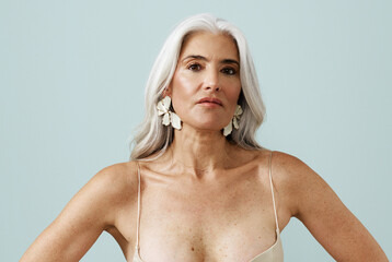 Confident Woman With Long Silver Hair Poses Against a Light Backdrop