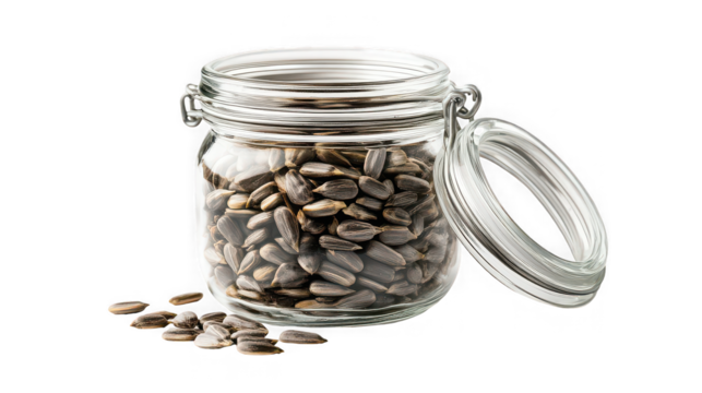 A clear glass jar filled with sunflower seeds and an open lid on a black background in studio shot