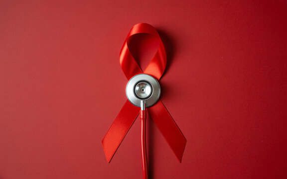 Red ribbon with stethoscope on red background symbolizing aids awareness and healthcare support - Powered by Adobe