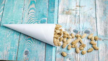 Boiled peanuts wrapped in cone-shaped paper on a rustic table