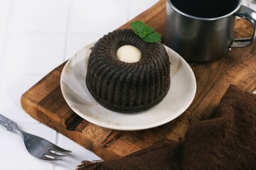 Black sticky rice cake or Bolu ketan hitam topped with Cream cheese and mint leaf, displayed on a white plate for food photography. © ROHE Creative Studio