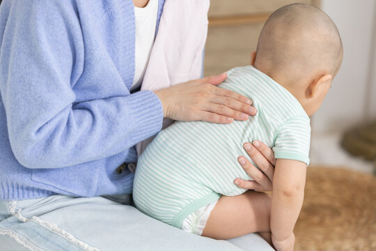 Close-up of Asian mother gently burping her baby after feeding, showing care and post meal routine. Ideal for parenting, children care, motherhood, infant health and early childhood lifestyle.