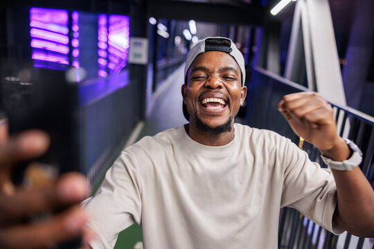 Joyful man celebrates with fist pump in urban setting.