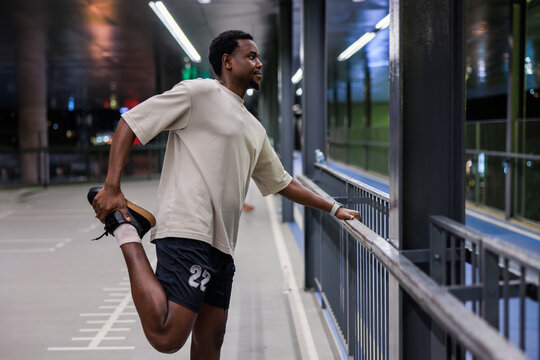 Man stretches leg on bridge before run.