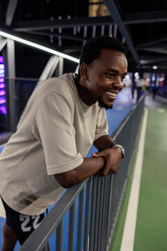 Smiling man leans on railing, looking into the distance.