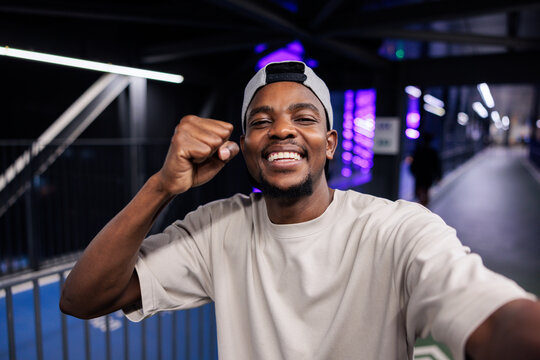 Smiling man in cap pumps fist in celebration.