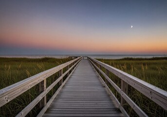Fototapeta premium Serene Wooden Boardwalk Path Over Coastal Dunes Leading to Ocean at Sunset with Crescent Moon
