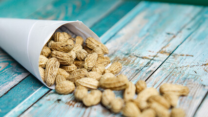 Boiled peanuts wrapped in cone-shaped paper on a rustic table
