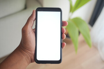 Hand holding smartphone in a bright indoor setting