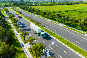 Aerial view of trucks driving on modern city road with greenery