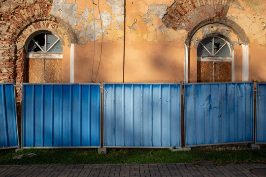 Construction fence in front of a building in need of renovation