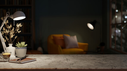 Books and coffee under lamp light on marble stone counter table across sofa chair in a dim lit room.