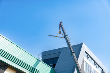 Mobile crane lifting a steel beam for roof installation on a modern industrial or commercial building.