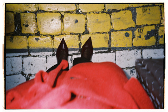 Stylish red outfit complements sharp heels on a bustling city street 