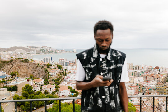 Black entrepreneur using phone overlooking coastal city