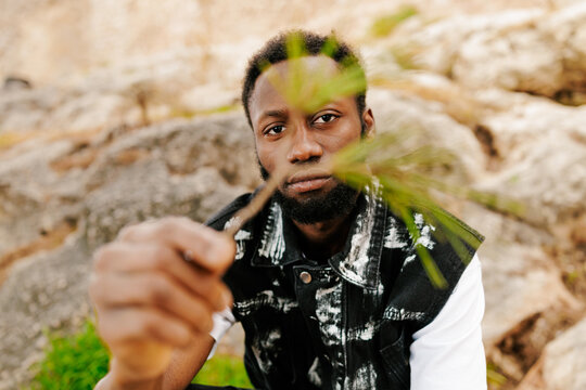 Young person holding a pine needle outdoors.