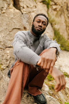 Man modeling distressed sweater and ripped pants outdoors