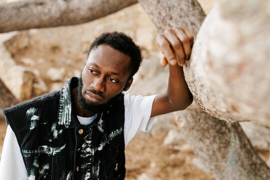 Young man contemplating nature while leaning on tree