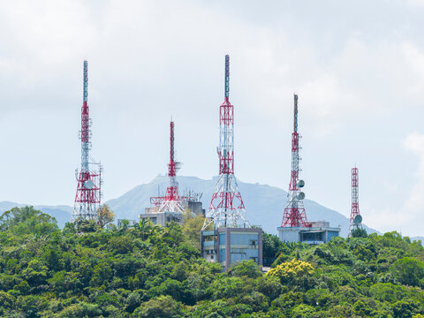 Communication towers on mountain with forest and buildings