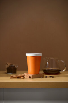 Coffee cup with cinnamon sticks and coffee beans on a wooden table.