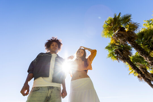 Two friend looking at camera in backlight over blue sky