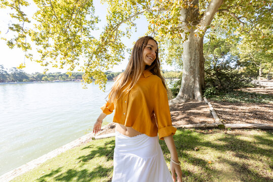 Young woman dancing freely in park in sunlight 