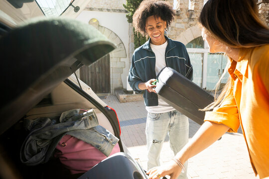 Couple picking luggage from car trunk when arriving to destination