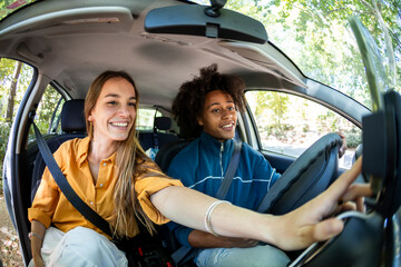 Two friends together in a car choosing music for the trip