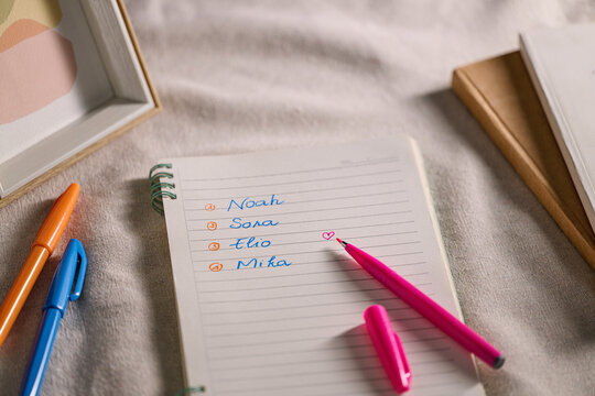 Baby name ideas written in a notebook with a pink pen