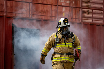 Portrait of firefighter in fireproof clothe walking out of the burning building full of ash and...