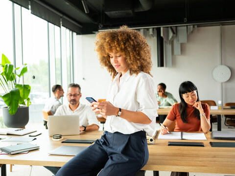 Young Professional Woman Using Phone in Bright Open Space Office