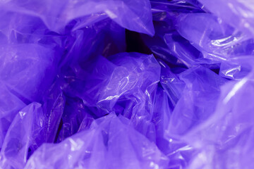 Macro view of crumpled purple plastic background creating chaotic abstract texture. shiny violet surface of wrapper reflects light, making dynamic and interesting pattern