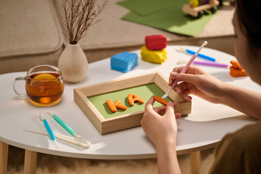 Person crafting with clay letters on a frame on a table