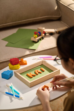 Person crafting the name 'Kai' with clay