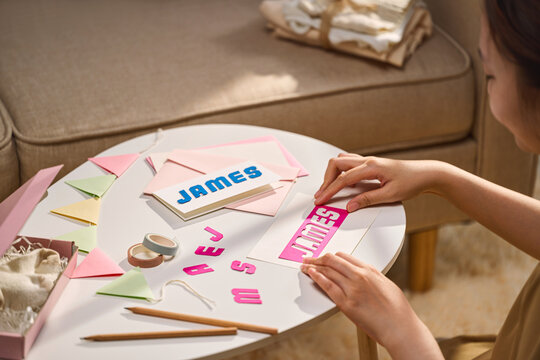 A woman is crafting a personalized card with the name James