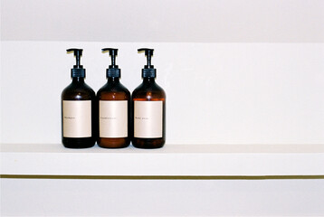Set of bottles with shampoo, conditioner and body soap on the shelf.